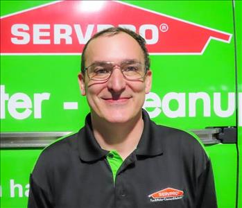 male employee with brown hair smiling in front of a green background